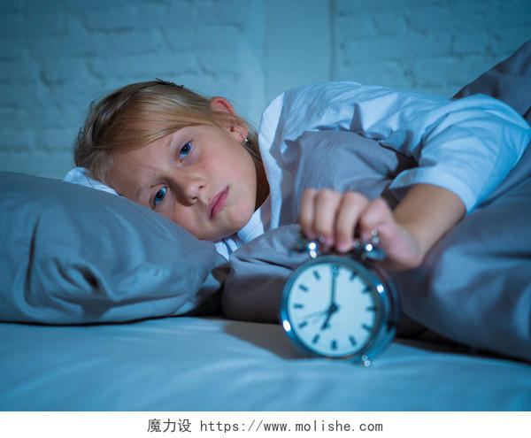 有睡眠障碍和失眠症的小女孩不眠不休的悲伤和愤怒的在床上看闹钟